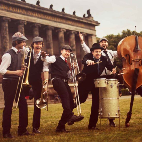 Die Jazzband German Trombone Vibration steht auf einer Wiese
